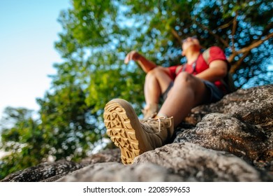Young backpacker man sitting and looking around on the rocky cliffs in forest with sunset after reach the destination, copy space