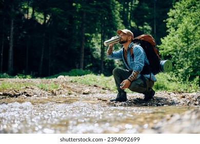 Young backpacker refreshing himself with fresh mountain creek water. Copy space. - Powered by Shutterstock