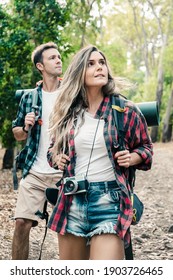 Young backpackers hiking, enjoying view and looking at landscape in forest. Caucasian attractive travelers walking on path in woods. Backpacking tourism, adventure and summer vacation concept