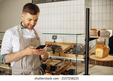 Young baker standing by the counter and talking on the phone - Powered by Shutterstock