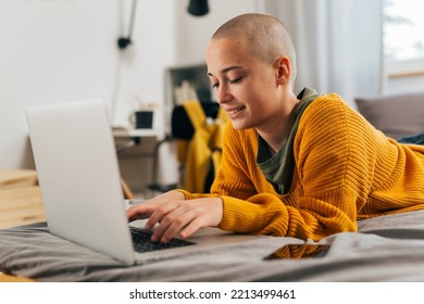 Young Bald Female Laying In Her Room And Using Laptop Computer