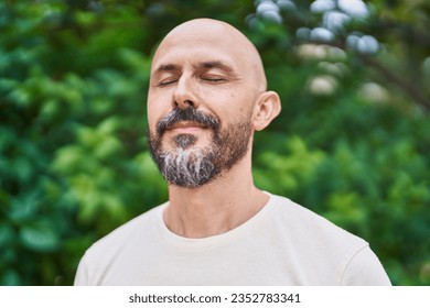 Young bald man breathing with closed eyes at park - Powered by Shutterstock