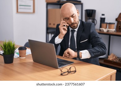 Young bald man business worker talking on smartphone looking watch at office - Powered by Shutterstock