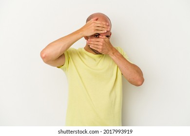 Young Bald Man Isolated On White Background Blink At The Camera Through Fingers, Embarrassed Covering Face.