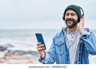 Young bald man smiling confident listening to music at seaside - Powered by Shutterstock