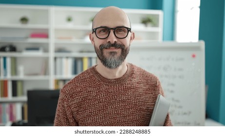 Young bald man teacher smiling confident standing at university classroom - Powered by Shutterstock