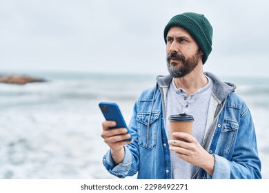 Young bald man using smartphone drinking coffee at seaside - Powered by Shutterstock