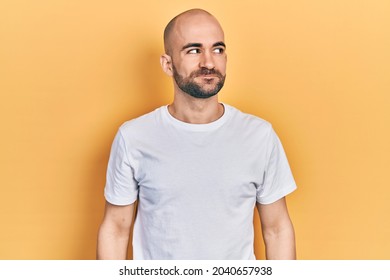 Young bald man wearing casual white t shirt smiling looking to the side and staring away thinking.  - Powered by Shutterstock