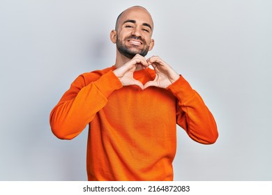 Young Bald Man Wearing Casual Clothes Smiling In Love Doing Heart Symbol Shape With Hands. Romantic Concept. 