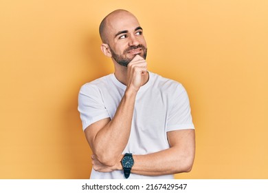 Young bald man wearing casual white t shirt with hand on chin thinking about question, pensive expression. smiling and thoughtful face. doubt concept.  - Powered by Shutterstock