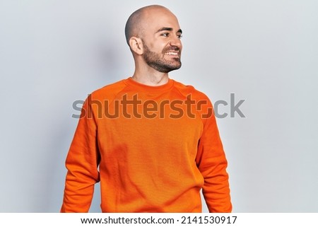 Young bald man wearing casual clothes looking to side, relax profile pose with natural face and confident smile. 