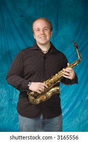 Young Balding Man Posing In Front Of Portrait Backdrop With Saxaphone