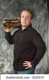 Young Balding Man Posing In Front Of Portrait Backdrop With Saxaphone