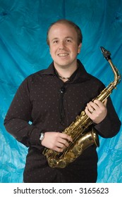 Young Balding Man Posing In Front Of Portrait Backdrop With Saxaphone