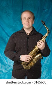 Young Balding Man Posing In Front Of Portrait Backdrop With Saxaphone