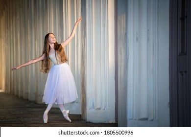 Young Balerina In A Long White Skirt With Long Loose Hair Stands In A Graceful Pose On Pointes