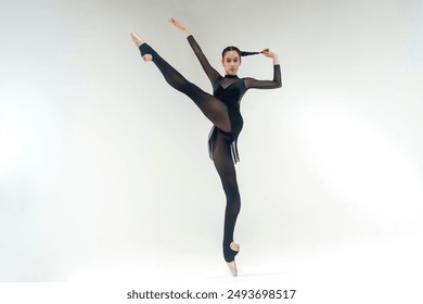 a young ballerina in a black leotard shows an eversion of the foot and plastic surgery, holding on to the braid, hanged - Powered by Shutterstock