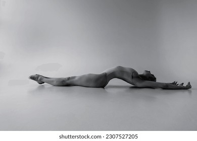 a young ballerina gymnast is lying right on the floor with her arms outstretched - Powered by Shutterstock