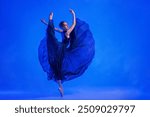 young ballerina in pointe shoes dances in a blue dress with a flying skirt among the fog