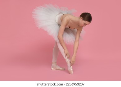 Young ballerina practicing dance moves on pink background - Shutterstock ID 2256953207