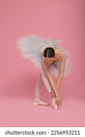 Young ballerina practicing dance moves on pink background - Shutterstock ID 2256953211
