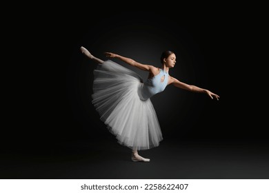 Young ballerina practicing dance moves on black background - Powered by Shutterstock