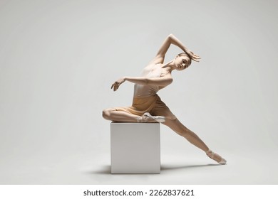 Young ballerina practicing dance moves on cube against white background. Space for text - Powered by Shutterstock