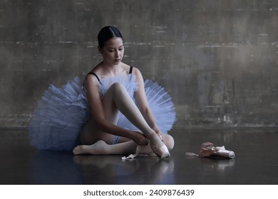 Young ballerina puts pointe shoes on her feet - Powered by Shutterstock