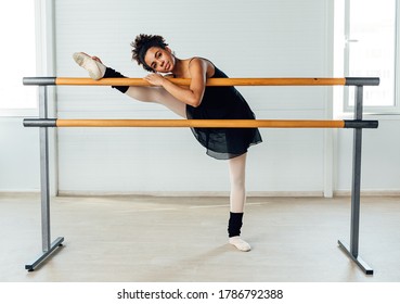 Young ballerina stretching her leg in dance studio. Woman doing exercise on ballet barre. - Powered by Shutterstock