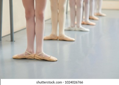 Young ballerinas legs in basic position. Group of little ballerinas standing in ballet position, cropped image. Classic ballet position.