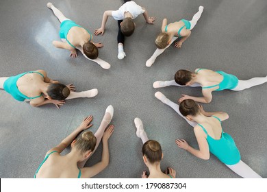 Young ballerinas perform various choreographic exercises sitting on the floor