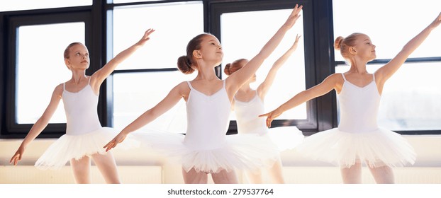 Young Ballerinas Practicing A Choreographed Dance All Raining Their Arms In Graceful Unison During Practice At A Ballet School