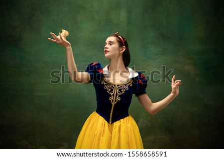 Young ballet dancer as a Snow White with poisoned apple in forest. Flexible caucasian ballerina dances like character of fairytail in bright clothes. Adorable and modern story in emotions.