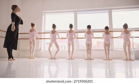 Young ballet students practicing basic positions at studio barre. Concept of beginner ballet education, foundational technique training, structured dance lessons, children learning process.
