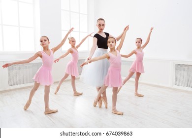 Young ballet teacher and students ballerinas in dance class. Girls are engaged in choreography in the ballet school.