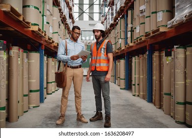 Young Banker In Conversation With Warehouse Manager Holding Digital Tablet Discussing Loan Details For Sanction