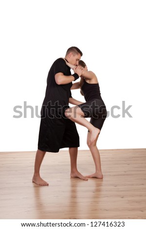 Young barefoot female kick boxer in training with her male instructor learning the moves as he demonstrates the technique