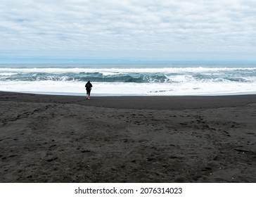 Young Barefoot Man Enjoying A Solitary Walk And Looking For Shells On The Beach Of Pichilemu On A Sunny Day.