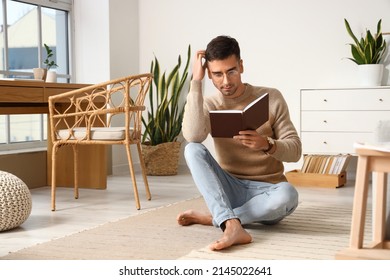 Young Barefooted Man Reading Book At Home