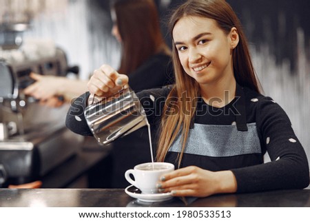Young barista girl makes coffee and smiles