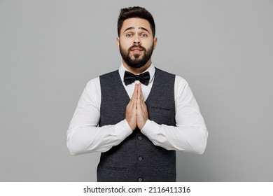 Young Barista Male Waiter Butler Man 20s Wear White Shirt Vest Elegant Uniform Work At Cafe Hands Folded In Prayer Gesture, Begging About Something Isolated On Plain Grey Background Studio Portrait.