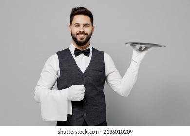 Young Barista Male Waiter Butler Man Wear White Shirt Vest Elegant Uniform Work At Cafe Hold In Hand Carrying Metal Tray Isolated On Plain Grey Background Studio Portrait. Restaurant Employee Concept