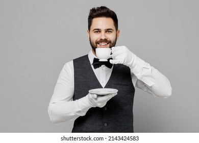 Young Barista Male Waiter Butler Man 20s Wear White Shirt Vest Elegant Uniform Work At Cafe Drink Coffee Hold Cup With Hot Beverage Isolated On Plain Grey Background Studio Restaurant Employee Concept