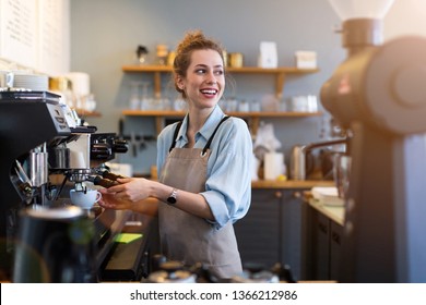 Young barista preparing coffee for customers at her cafe counter