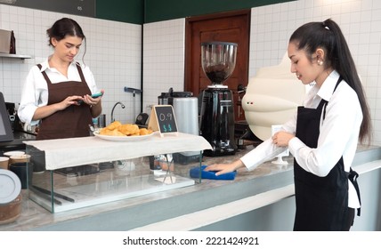 Young Barista And Waitress Women Are Standing At Cafeteria Counter Bar Preparing Orders And Cleaning. Two Lesbian Women Couple Manage A Small Coffee Shop Business Together. LGBTQ Lifestyle.