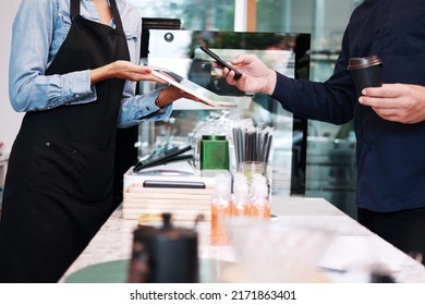 Young barista woman is holding tablet for customer using smart phone scan QR code on tablet for payment at counter bar at coffee shop. Technology of digital pay without money concept. - Shutterstock ID 2171863401