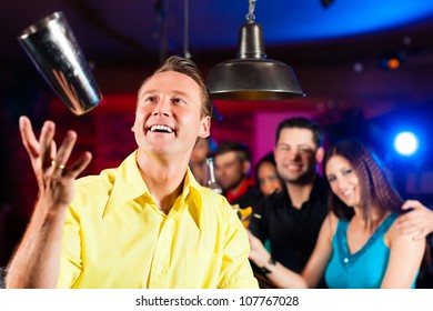 Young Barkeeper In A Pub Is Mixing Cocktails Or Drinks And Is Doing Tricks With The Shaker