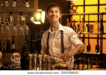 Young bartender pouring tequila in bar at night