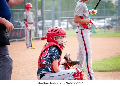 Young baseball boy catcher getting signals from coach with referee.