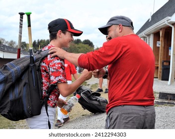 Young baseball player boy with bat bag getting fist bump celebration from fan dad after a playing pitching a no-hitter great game on the mound. - Powered by Shutterstock